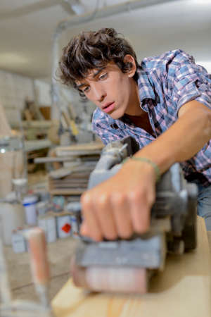 Young carpenter using a belt sanderの写真素材