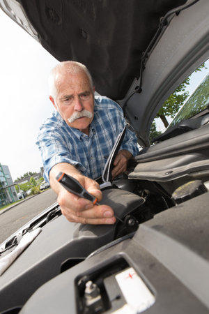 retired man servicing his car engine