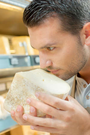 Cheese shop worker smelling on of his cheesesの写真素材