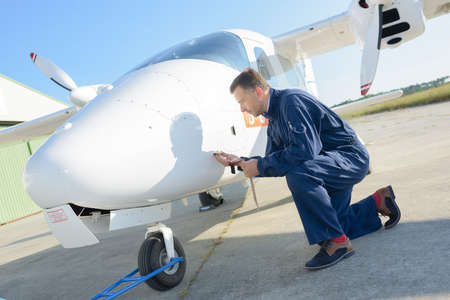 Mechanic knelt down looking at aircraftの写真素材