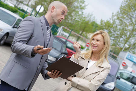 attractive salesman showing new car to a customerの写真素材