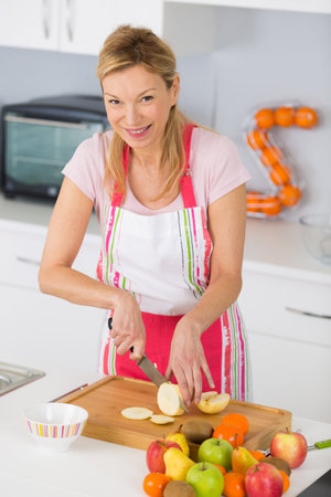 close-up on mature female hands slicing apples on chopping boardの写真素材
