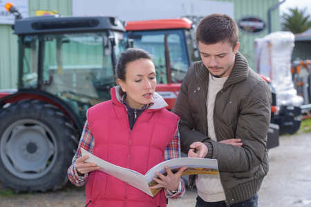 saleswoman try to sell new tractor to farmerの写真素材