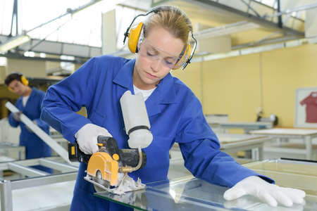 Woman cutting glass in factoryの写真素材