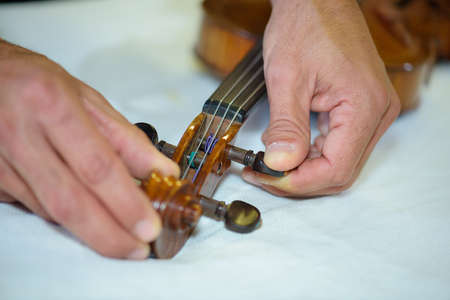 Man adjusting strings on violinの写真素材