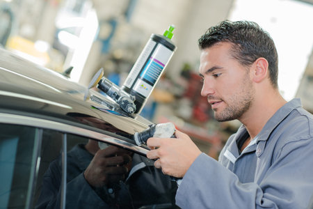 Man polishing roof of car with air powered machine