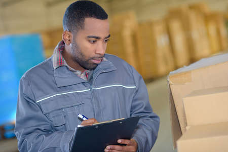 worker writing an information from a boxの写真素材