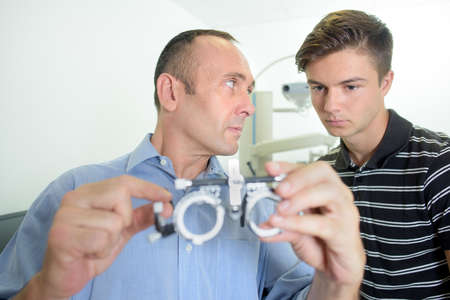 Optician showing eyetest glasses to traineeの写真素材