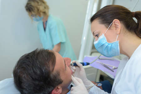 Dentist using implement on patient's teethの写真素材