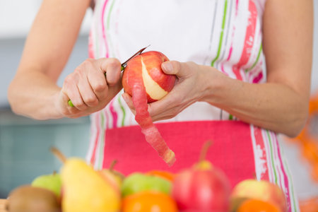 elder woman peeling apples in her kitchen