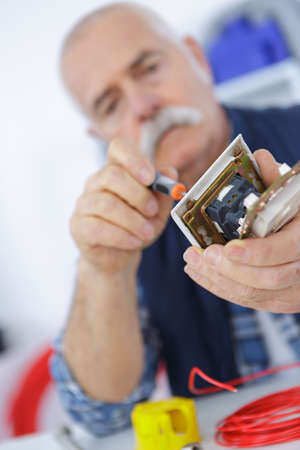 senior male tech tests electronic equipment in service centreの写真素材