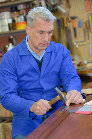 portrait of retired carpenter sitting at his workshopの写真素材