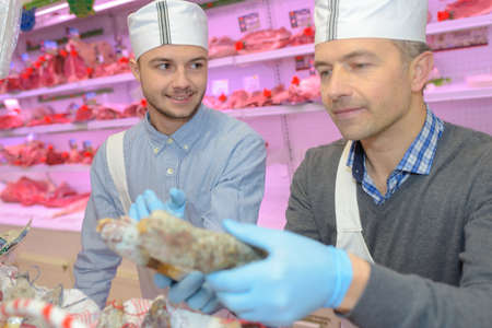 Butcher holding two dried sausagesの写真素材