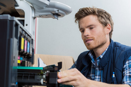 young male technician is repairing a printer at office
