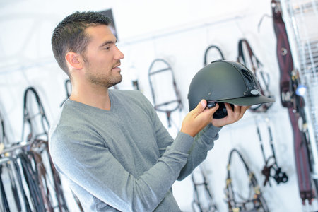Man in equestrian shop holding riding hat