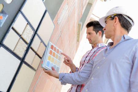Two men matching colour samples on exterior wallの写真素材