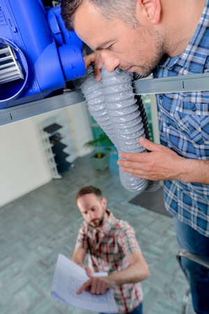 man showing plans to builder in roof spaceの写真素材