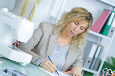 young attractive needlewoman at studio working with sewing machine