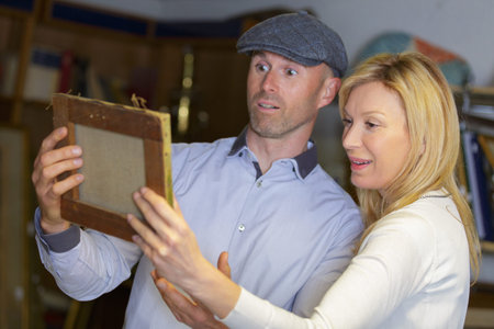 cheerful couple looking at creative picture in art gallery