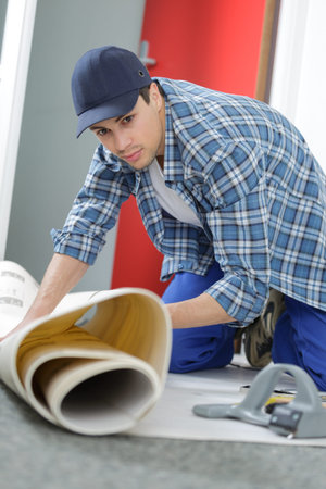 adult worker removing old carpet in room