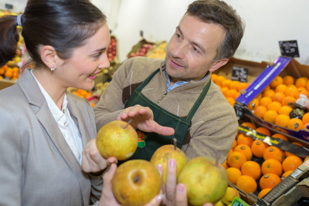 Greengrocer advising customer about applesの写真素材