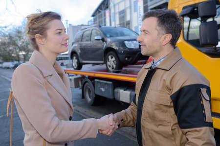 Recovery driver shaking hands with owner of carの写真素材