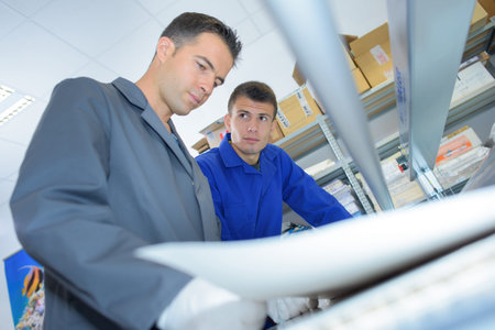 Two gloved technicians using printing machine