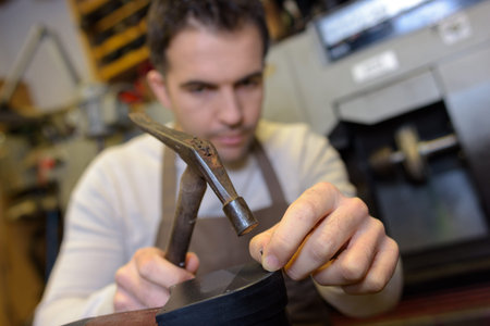 Cobbler hammering nail into heel of shoe