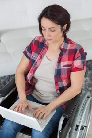 woman in a wheelchair typing on laptop