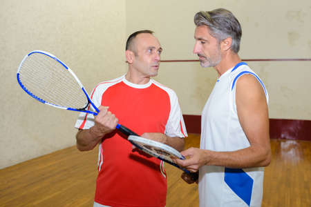 Men on squash court, talkingの写真素材