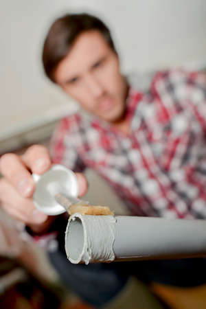 Man putting plastic glue on end of pvc pipeの写真素材