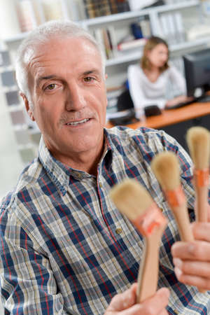 Office worker holding paint brushesの写真素材