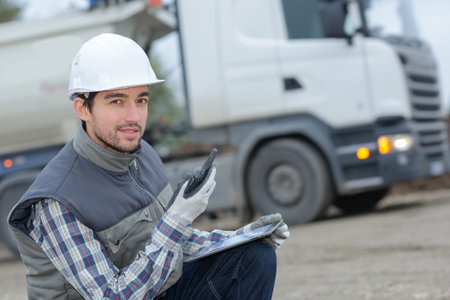 Man on construction site holding walkie talkie