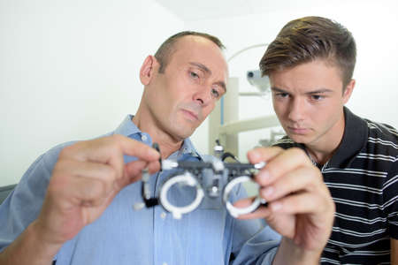 Optician showing test glasses to young manの写真素材