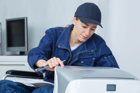 Woman in wheelchair repairing applianceの写真素材
