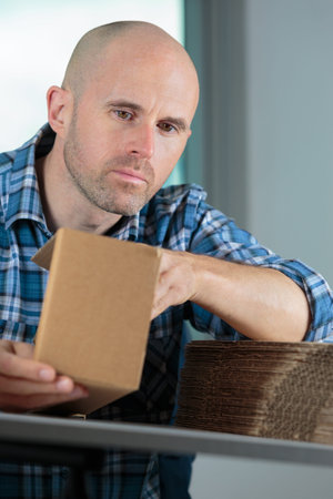 man folding cardboard into packaging