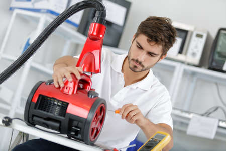 handsome young repairman fixing vacuum cleanerの写真素材