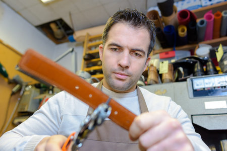 Man making hole in leather belt
