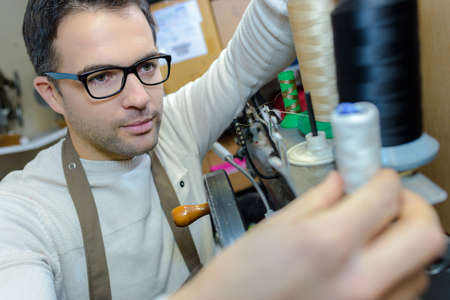 Man changing cotton reel on machineの写真素材