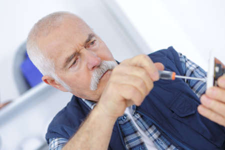 senior adult electrician checking and repairing plugの写真素材