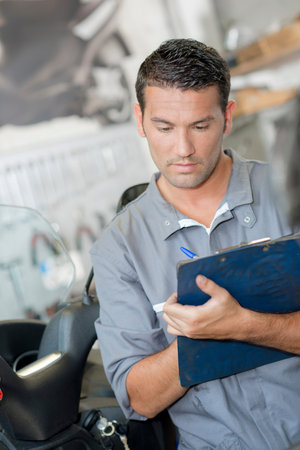 Mechanic making notes on clipboard