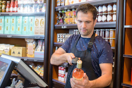 Checkout clerk scanning bottle of wineの写真素材