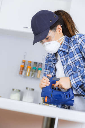 Woman using electrical jigsawの写真素材