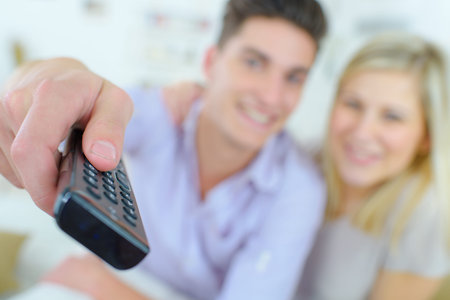 couple sitting in sofa and watching tv