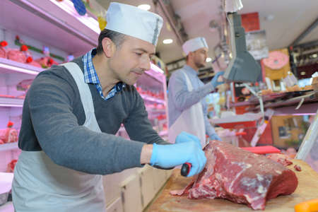 butcher teaching a young one how to sell meatの写真素材