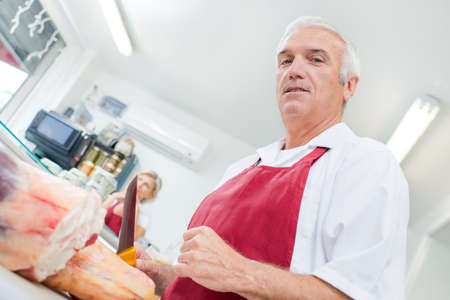 Upward view of butcher holding knifeの写真素材