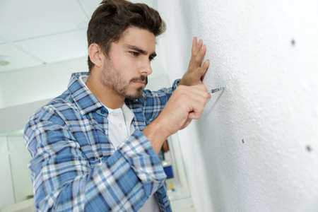 skilled electrician preparing holes before installing applianceの写真素材