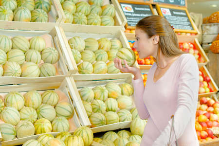 Lady smelling melon in grocersの写真素材