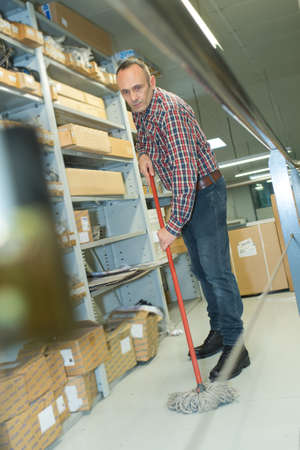 Man mopping floor of warehouseの写真素材