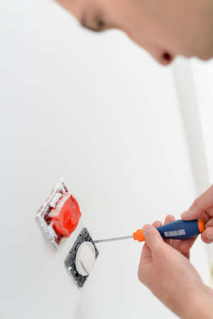 Electrician screwing socket to wallの写真素材